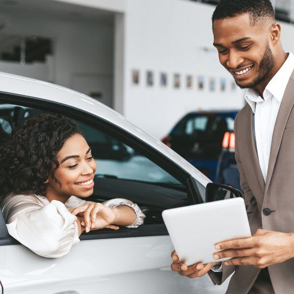 a woman smiling at a screen a salesman is showing her